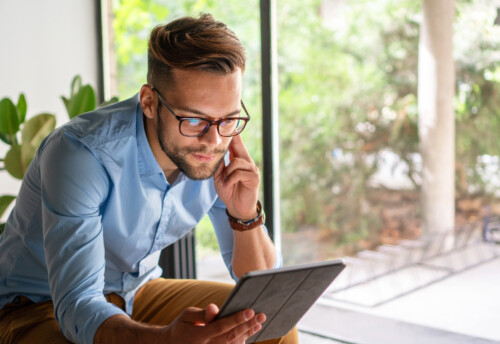 Young man smiling looking at digital tablet